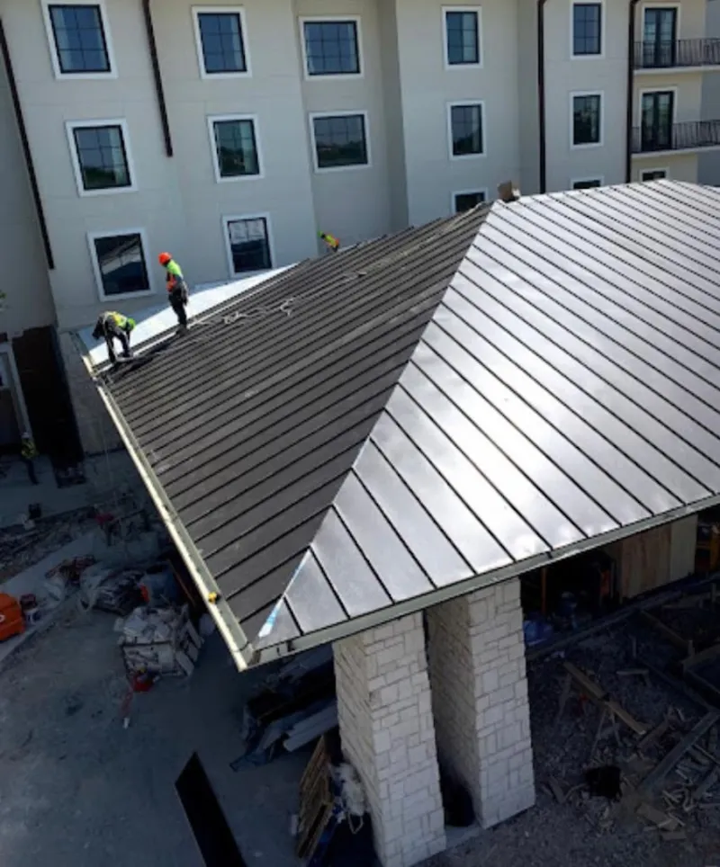 Crew installing standing seam metal roof panels on a commercial project in Elfers
